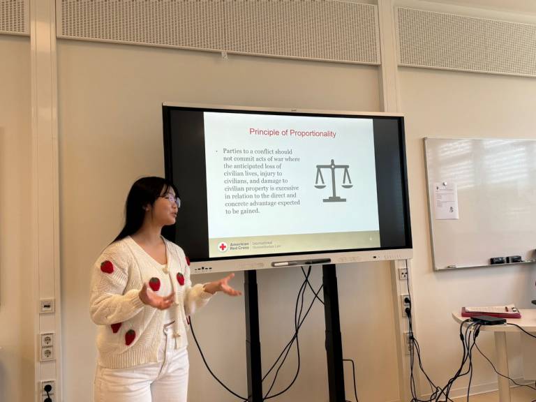 Rachel Oh stands before a smart board presenting to her peers on the importance of International Humanitarian Law